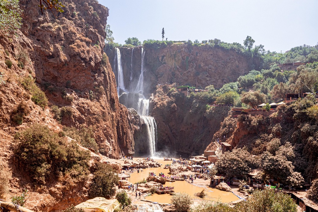 Cascades d'Ouzoud entourées de falaises rouges et d'oliviers verts au Maroc
